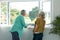 Back view of caucasian senior couple standing at window and talking