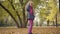Back view of a Caucasian teenage girl walking in the autumn park, turning back and looking at the camera. Cute teenager