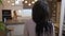 Back view of Caucasian woman with long black hair standing in furniture store as girl choosing kitchen at background
