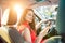 Back view caucasian young woman driver using touch screen smartphone and hand holding steering wheel in a car during driving.