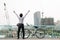 Back view of cheerful man with hands up with bicycle