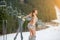 Back view of cheerful naked female skier. Smiling girl is posing with skis on snowy slope