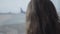 Back view close-up of Caucasian girl with curly hair looking at airplane takeoff through the big airport window. Child
