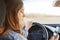 Back view of concentrated female driver sits in car, holds modern cell phone, types messages or reads news online, has break after