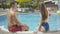 Back view of confident brunette man flirting with slim young woman at poolside. Portrait of rich Caucasian tourists