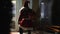 Back view confident man in Santa Claus costume walking outdoors on snowy night knocking in door. Guy with gifts bag