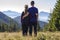 Back view of couple athletic boy and blond girl standing together embraced enjoying breathtaking view of magnificent Carpathian m