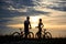 Back view of couple cyclists standing with bicycles and enjoying the sunset