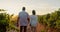 Back view, couple and holding hands in vineyard in countryside, travel and holiday in Italy. Mature people outdoor