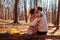Back view of couple hugging in autumn forest. Man and woman sitting on trunk enjoying fall landscape on date