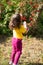 Back view. cute curly girl child in a yellow T-shirt and burgundy pants picks rowan berries