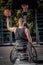 Back view of a disabled basketball player in wheelchair spinning basketball on his finger on open gaming ground.