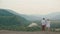 The back view from drone on the happy loving couple holding hands while standing on the edge of the mountains and