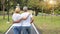 Back view elderly couple with white shirt and blue jean embracing and walking in park in summer time