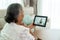 Back view of elderly woman making video call with her doctor with her feeling sore throat on digital tablet online healthcare