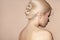 Back view of elegant bunch hairstyle. Beautiful woman with blond hair on beige. Wedding or evening salon style coiffure