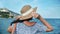 Back view elegant travel woman in straw hat admiring seascape. Medium shot on RED camera