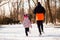 Back view of father and daughter in colored jackets running through winter park. Family spend time outdoors with health