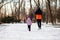 Back view of father and daughter in colored jackets running through winter park. Family spend time outdoors with health