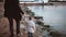 Back view of father and son on the beach holding hands and walking along the shore at sunset.