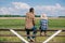 back view of father and son sitting on fence and looking at green