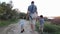 Back view of father with two young sons walking on the path in the park