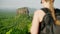 Back view of female hiker with backpack admires ancient Sigiriya Rock fortress. Explorer on Pidurangala Rock observes