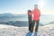 Back view of female snowboarder standing with snowboard and enjoying mountain landscape