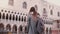 Back view female tourist with backpack stands excited looking at San Marco square building in Venice, Italy slow motion.