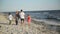 Back View of Four Members of Happy Family Walking on the Beach During Summer Vacation on the Seaside.