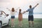 Back view of Freedom family father, mother and daughter having fun on a tropical beach and a car on the sider. Family vacation