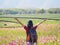 Back view of freedom tourist woman raises her arm in colorful cosmos flower field