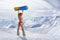 Back view of girl in bikini holding snowboard above head