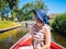 Back view of girl with blond hair and blue hat sit on a boat ride at the river in famous typical Dutch village Giethoorn