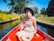 Back view of girl with blond hair and blue hat sit on a boat ride at the river in famous typical Dutch village Giethoorn
