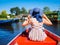 Back view of girl with blond hair and blue hat sit on a boat ride at the river in famous typical Dutch village Giethoorn