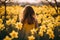 Back view of girl child in field of yellow Daffodil spring flowers