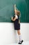 Back view of girl drawing with chalk on blackboard