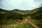 The back view of a girl hiker hiking to the top of Spytsi mountain, Carpathians, Ukraine. He has a long stick in his hands. Travel