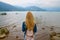 Back view of girl standing near water and looking at horizon with mountains