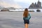 Back view of girl walking reflexive e tranquil on hidden amazing black beach on sunrise. Young female discovering wild paradisiac