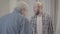 Back view of grey-haired Caucasian retiree shouting at young man indoors. Displeased senior father scolding adult son at