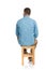 Back view of grizzled hair man in denim shirt sitting on wooden chair