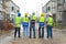 Back view of Group of happy contractors, engineers and formats in safety vests with helmets stand on the under-construction