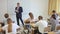 Back view of group of teenage students studying in classroom with male teacher