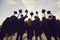 Back view of group of university graduates holding academic caps before throwing them in air