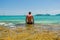 Back view of a handsome man sitting on the stone and looking on the boats in the sea l. Selective focus on tired male on