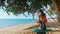 Back view of happy barefoot girl on swing in tropical beach