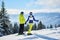 Back view of happy couple skiers standing on mountain edge, holding hands, enjoying winter mountain panoramic landscape