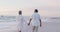 Back view of happy hispanic just married senior couple walking on beach at sunset